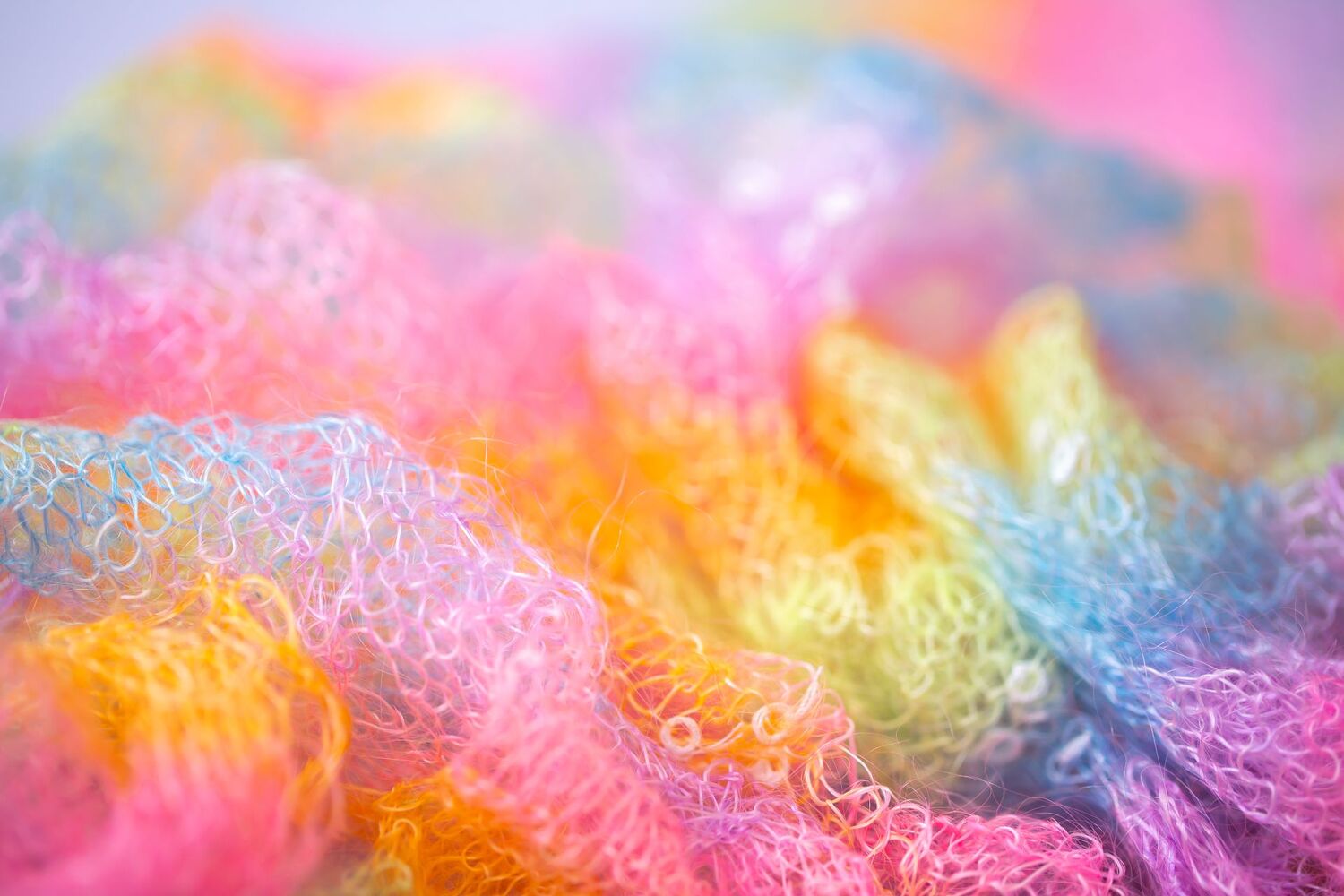 Knitted surface woolen items rainbow colored as a background. Closeup of soft multicolored knitted texture patterns. Warm winter clothes. Background textile surface with copy space for text. blurred / Vera - stock.adobe.com